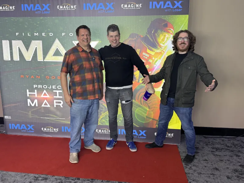 Game Informer editor in chief Matt Miller (left), former GI editor and Firaxis writer Ben Reeves (center), and executive editor Kyle Hilliard (right) hanging out with a big picture of Ryan Gosling.